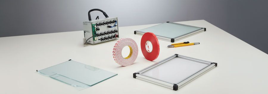 3M VHB Clear tape bonding glass and acrylic panels, creating nearly invisible bond lines